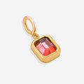 A collection of gold-colored birthstone charms with different colored gemstones, arranged in a row.