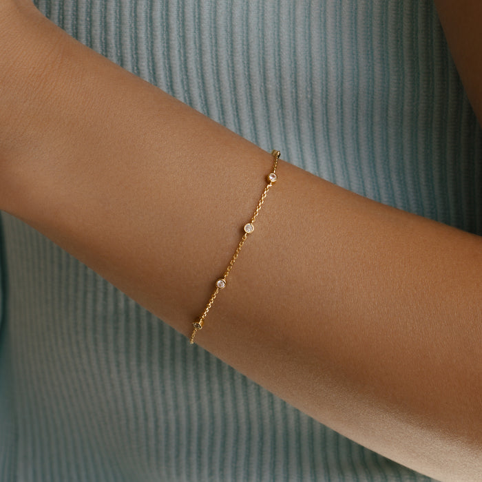 Gold bracelet with small beads on a wrist against a white background