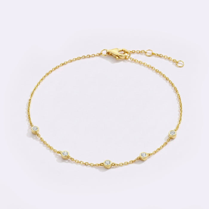 Gold bracelet with small diamonds on a light gray background
