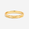 A gold ring with a textured hatched pattern, displayed against a black background.
