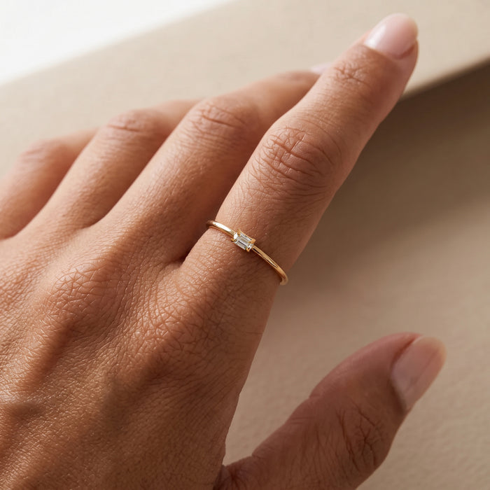 Gold ring with a purple gemstone on a hand against a black background