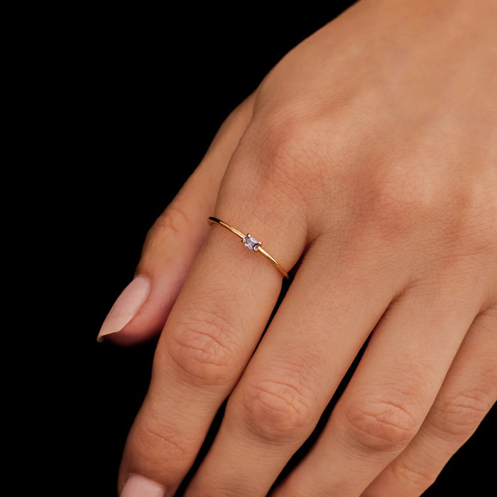 Close-up of a hand wearing two gold rings on a black background