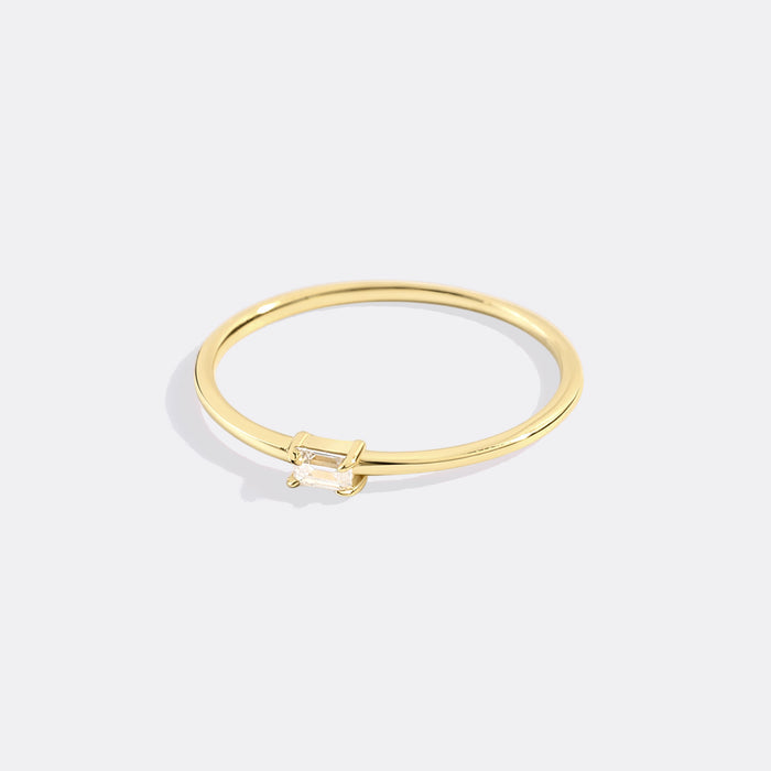 Gold ring with a small diamond on a light gray background