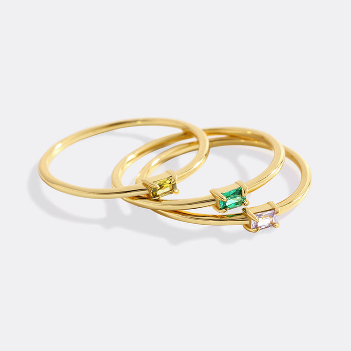 Three gold rings with gemstones on a white background