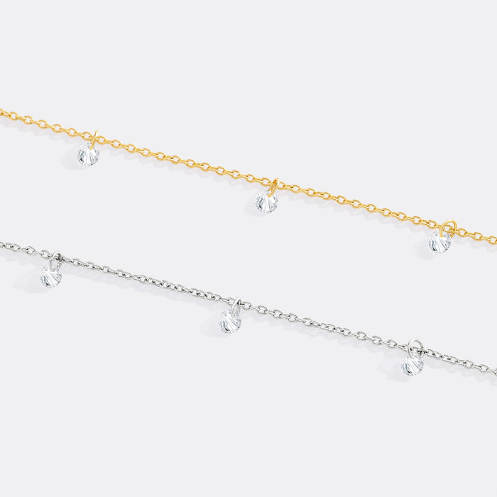 Two gold and silver anklets with clear crystals on a white background