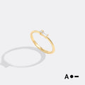 Gold ring with a diamond on a light gray background
