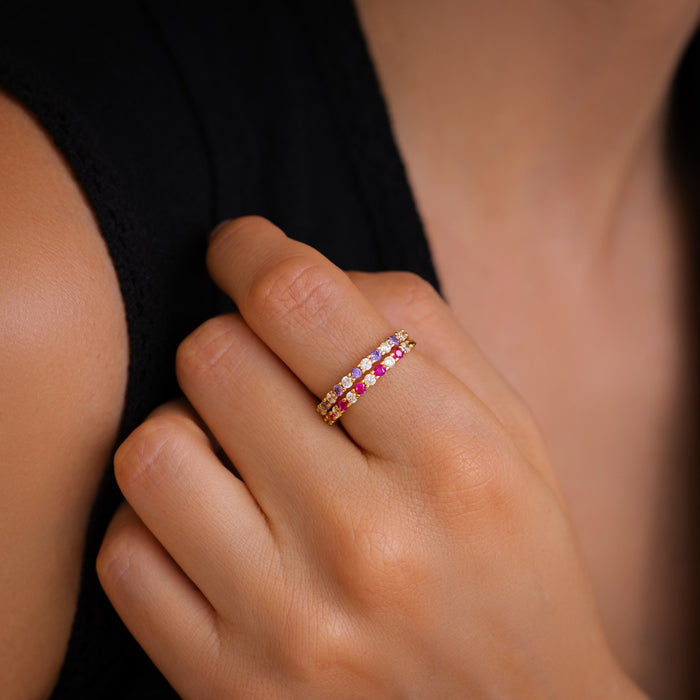 Close-up of a hand wearing a gold ring with gemstones on a blurred background
