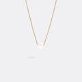 Gold necklace with a single pearl pendant on a white background