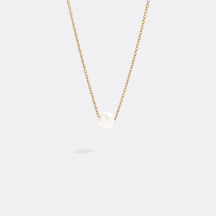 Gold necklace with a single pearl pendant on a white background