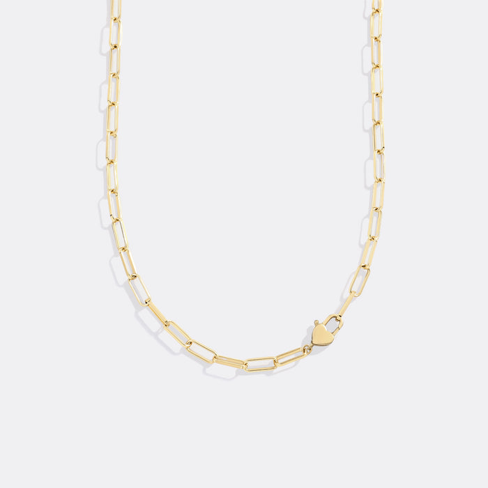 Gold chain necklace with a heart pendant on a light gray background