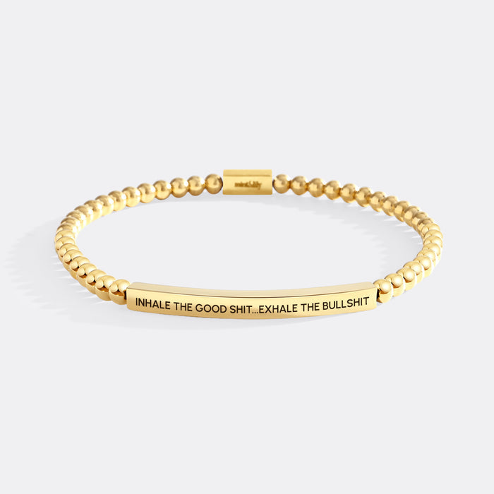 Gold beaded bracelet with engraved text on a white background