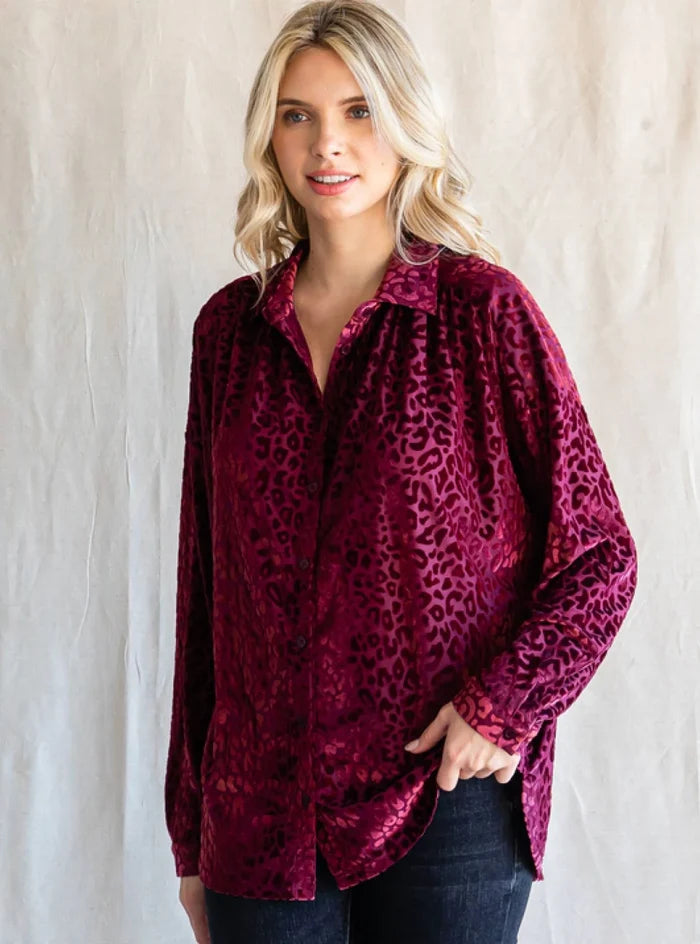 Woman wearing a burgundy leopard print shirt against a plain background