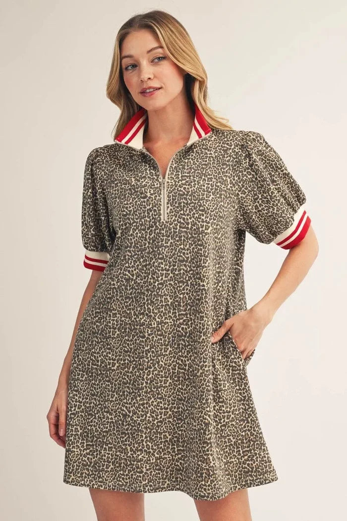 Woman wearing a patterned dress with red and white accents on a plain background