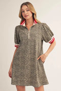 Woman wearing a patterned dress with red and white accents on a plain background