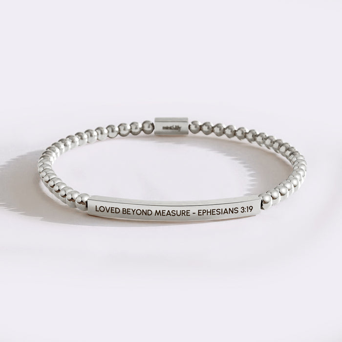 Silver beaded bracelet with engraved text on a white background