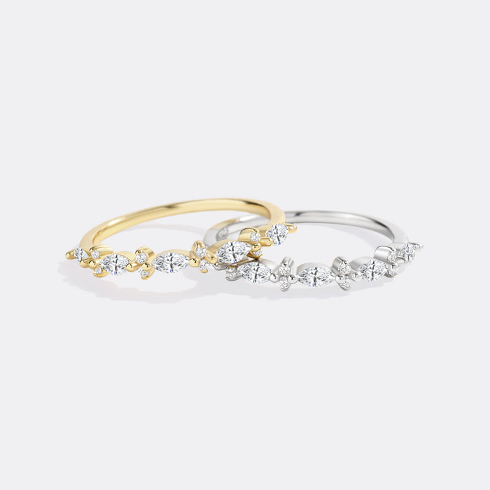 Two diamond-studded rings, one gold and one silver, on a light gray background.