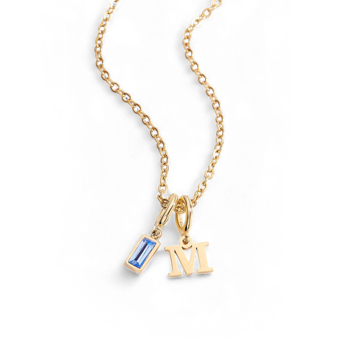 Gold necklace with a blue gemstone pendant and 'M' letter pendant on a white background