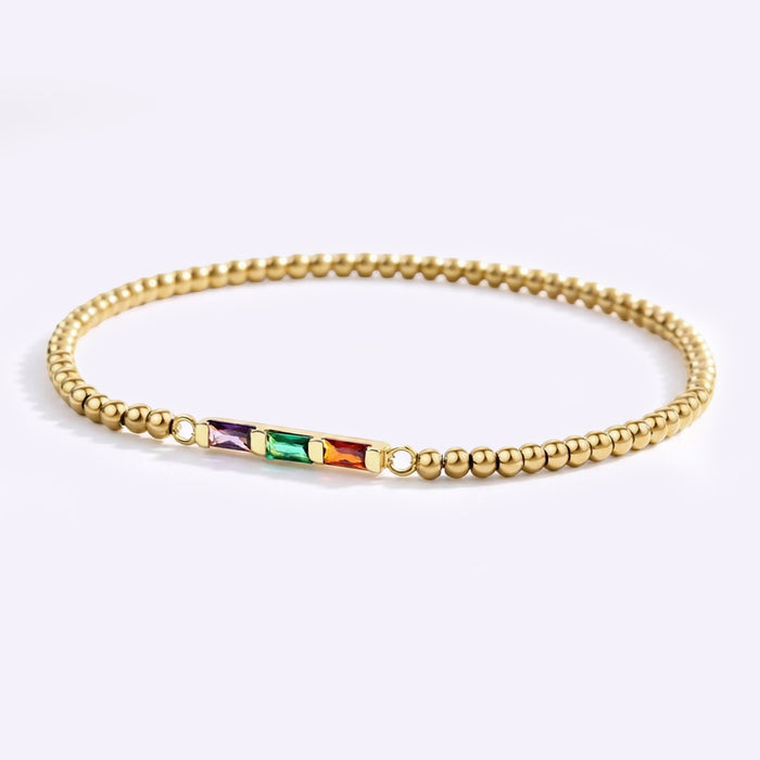 Gold beaded bracelet with colorful beads on a light gray background