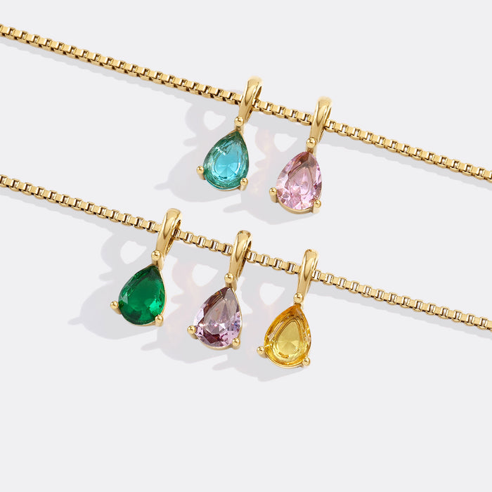 Gold necklaces with teardrop-shaped gemstones on a white background
