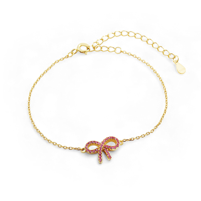 Gold bracelet with a bow-shaped charm on a black background