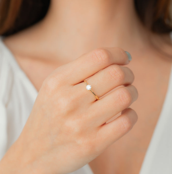 Close-up of a hand wearing a diamond ring on a neutral background