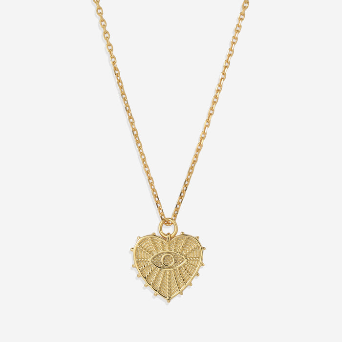 A gold-colored pendant necklace with a heart-shaped charm featuring an evil eye design in the center, displayed against a white background.
